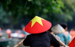En lokal kvinna i traditionell hatt ror sin båt genom det vackra landskapet i Ninh Binh